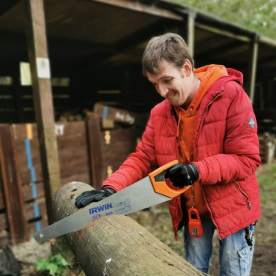 An Earthworker using a saw to cut a log of wood