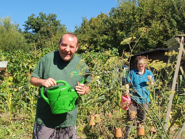 Two Earthworkers caring for the market garden, holding watering cans