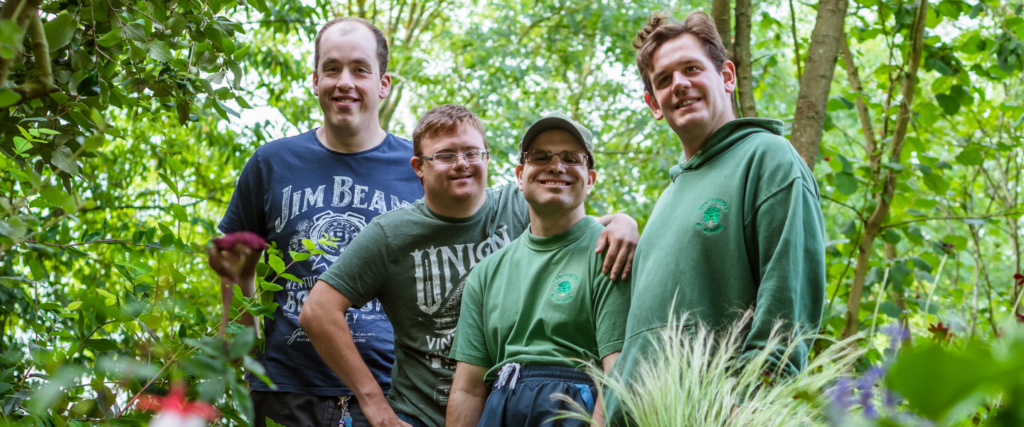 Four Earthworkers smiling together in the Earthworks garden
