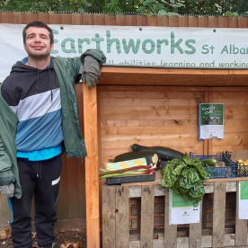 An Earthworker standing alongside a table of garden produce