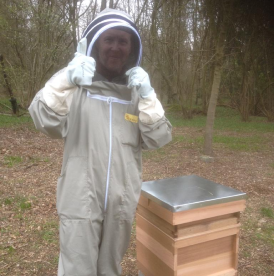 One of our trustees in a beekeeper suit next to one of our beehives