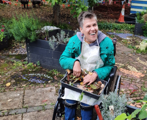 An Earthworker in a wheelchair holding a tray for plants