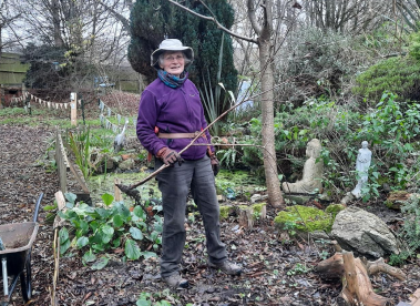 An volunteer holding a tree branch in the gardens