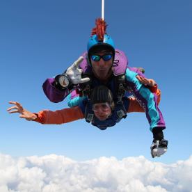 Two people skydiving on a bright day with blue sky