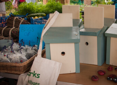 A selection of market goods including wooden bird houses, and an Earthworks canvas bag