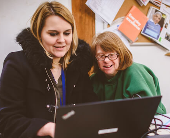 An Earthworker sat next to a volunteer in front of a laptop