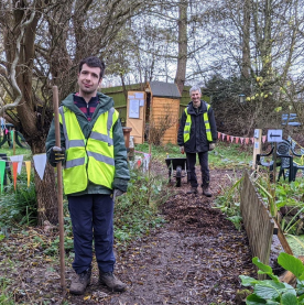 An Earthworker and a member of staff wearing hi-vis jackets working in the gardens