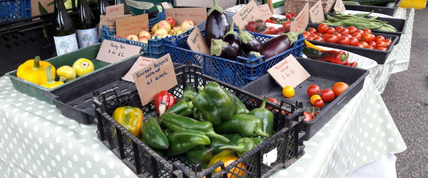 A view of an Earthworks stand at a Farmers Market, displaying fresh fruit and vegetables amongst other produce