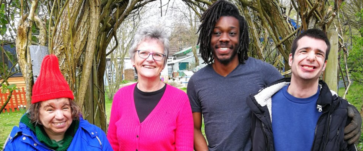 Two Earthworkers, former Trustee and former support worker smilling, stood alongside each other outside