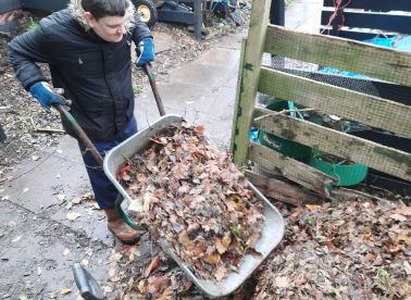 An Earthworker offloading some leaves into the compost area
