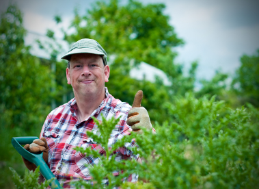 An Earthworker behind a hedge with his thumbs up