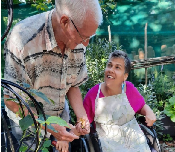 An Earthworker in a wheelchair smiling and talking with her family member