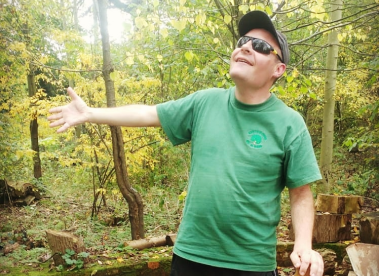 An Earthworker with sunglasses with his arm outstretched in our native woodland